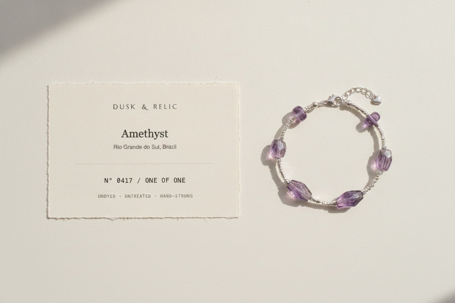 A printed identification card on heavy cotton stock, with the crystal bracelet laid on the plaster beside it